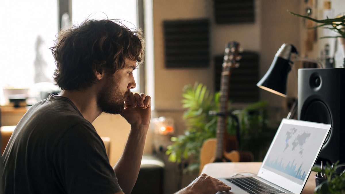 An independent artist reviewing Spotify listening data on a laptop in a home studio, planning a release