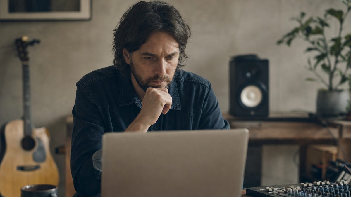 An independent artist reviewing streaming analytics on a laptop in a home studio, checking for irregular activity
