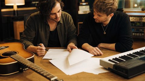 A songwriter reviewing a publishing contract at a desk with pen in hand