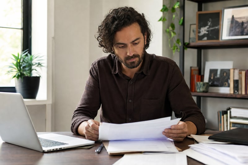 A songwriter reviews music registration documents at a desk