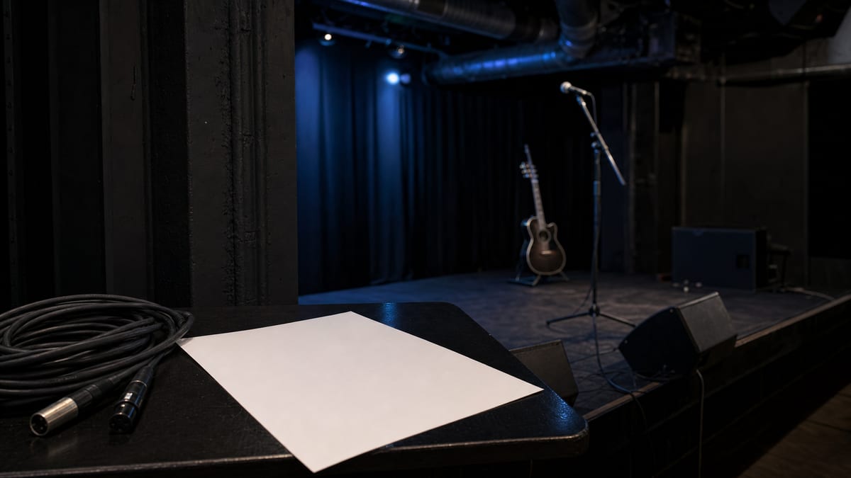 An empty blue-lit club stage with a blank sheet, cable, microphone stand, and guitar resting on a stand, with no readable text or logos.