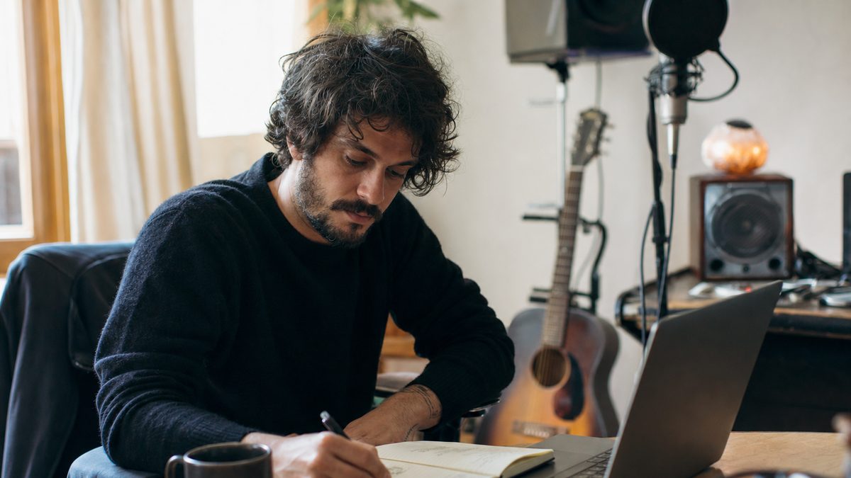 An independent musician preparing a release submission on a laptop in a home studio before sending it for editorial consideration