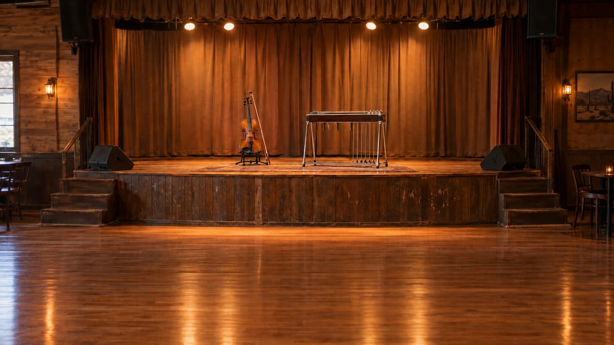 Photorealistic editorial scene of a fiddle and pedal steel on a dance-hall stage, with an open floor behind.