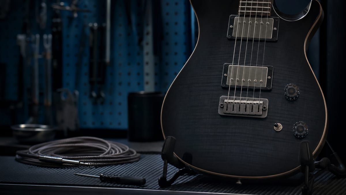A close editorial photograph of an electric guitar resting on a stand with two unbranded pickups visible under the strings, cool studio light, no readable text or logos.
